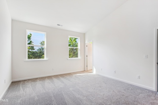 carpeted spare room with lofted ceiling