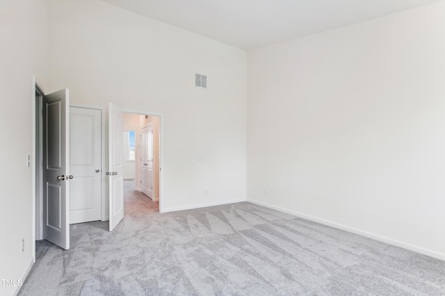 unfurnished room featuring light carpet and a high ceiling