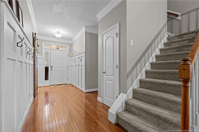 foyer featuring stairway, baseboards, light wood finished floors, and ornamental molding