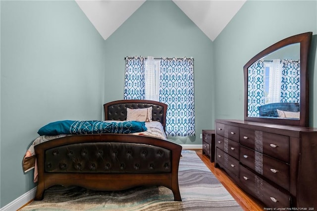 bedroom featuring lofted ceiling, wood finished floors, and baseboards