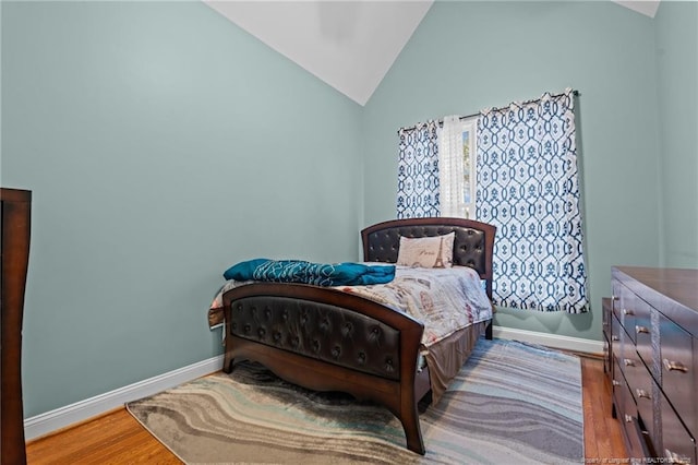 bedroom featuring lofted ceiling, wood finished floors, and baseboards