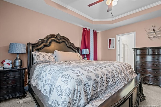 carpeted bedroom with ceiling fan, crown molding, and a tray ceiling