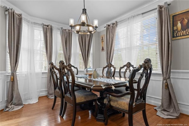 dining area with a notable chandelier, hardwood / wood-style floors, and a decorative wall