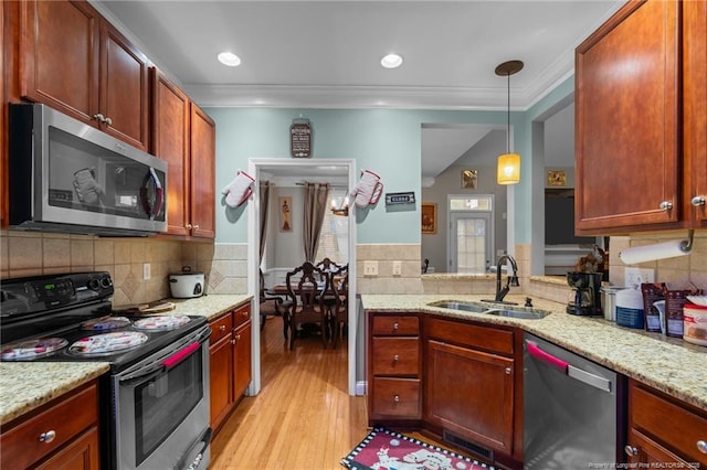 kitchen with a sink, crown molding, light wood-style flooring, and stainless steel appliances