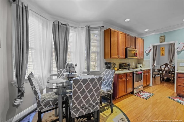 kitchen featuring backsplash, ornamental molding, appliances with stainless steel finishes, light wood-style floors, and brown cabinetry