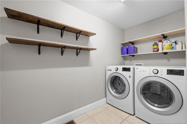 laundry room featuring light tile patterned floors, baseboards, laundry area, and washing machine and clothes dryer