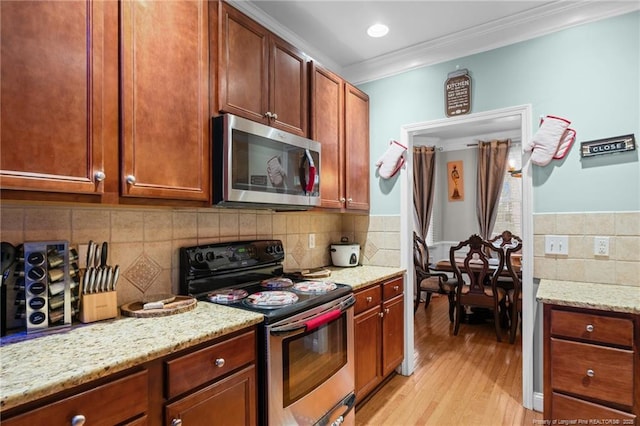 kitchen with light stone counters, light wood finished floors, ornamental molding, decorative backsplash, and stainless steel appliances