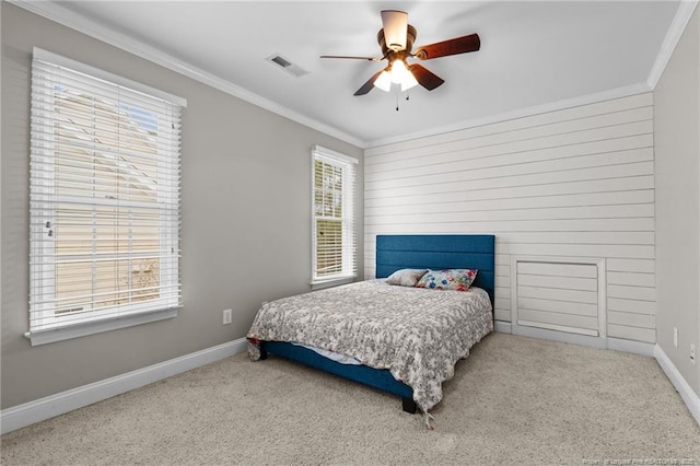 carpeted bedroom with visible vents, a ceiling fan, crown molding, and baseboards