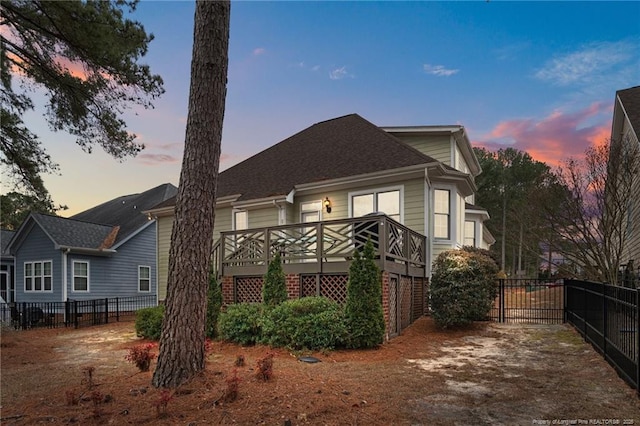 back of property at dusk with a wooden deck and fence