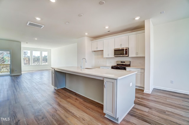851 Parc Townes Dr Unit 10, Wendell, NC 27591 - kitchen featuring appliances with stainless steel finishes, white cabinetry, an island with sink, sink, and light hardwood / wood-style floors
