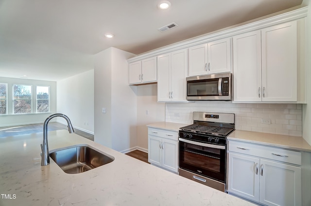 851 Parc Townes Dr Unit 10, Wendell, NC 27591 - kitchen featuring sink, appliances with stainless steel finishes, white cabinetry, backsplash, and light stone countertops