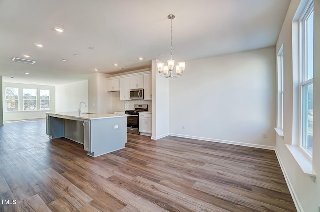 851 Parc Townes Dr Unit 10, Wendell, NC 27591 - kitchen with hardwood / wood-style floors, decorative light fixtures, white cabinets, a kitchen island with sink, and stainless steel appliances