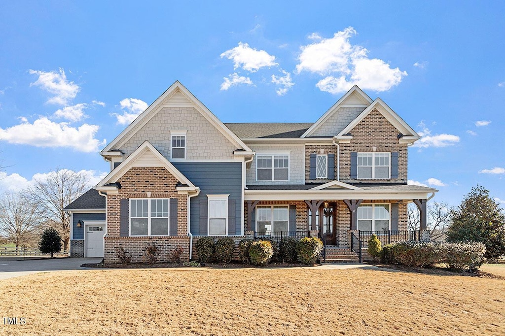 craftsman-style home with a front yard, covered porch, and a garage