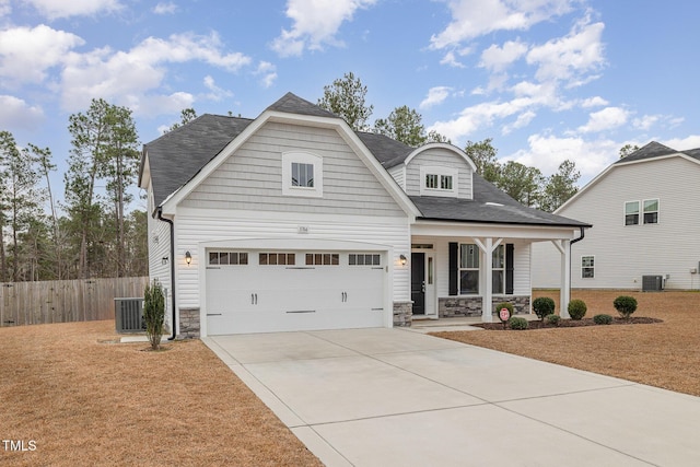 view of front of house with covered porch, a garage, and central AC unit