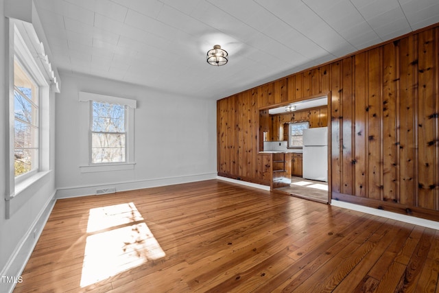 unfurnished living room featuring wood walls and light hardwood / wood-style floors