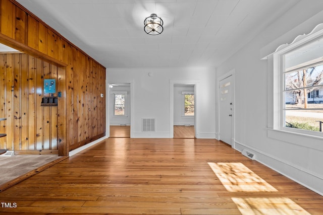 interior space featuring plenty of natural light, wood walls, and light hardwood / wood-style flooring