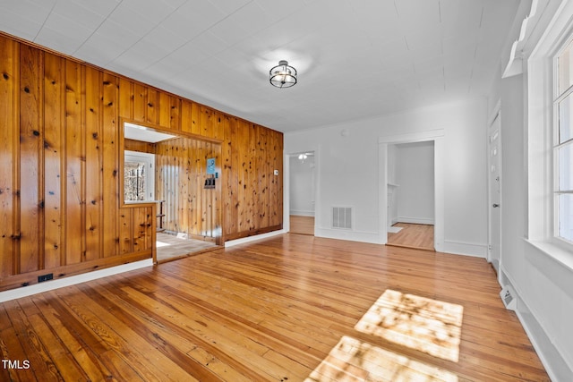 unfurnished living room featuring light hardwood / wood-style floors and wood walls