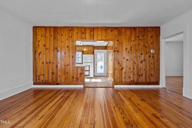 spare room with hardwood / wood-style floors, crown molding, and wood walls