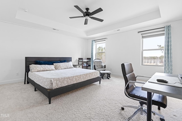 carpeted bedroom featuring a tray ceiling and ceiling fan