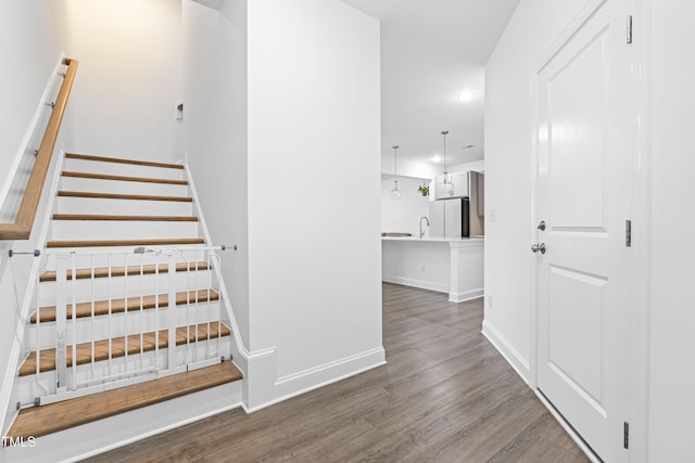 stairs featuring hardwood / wood-style floors and sink