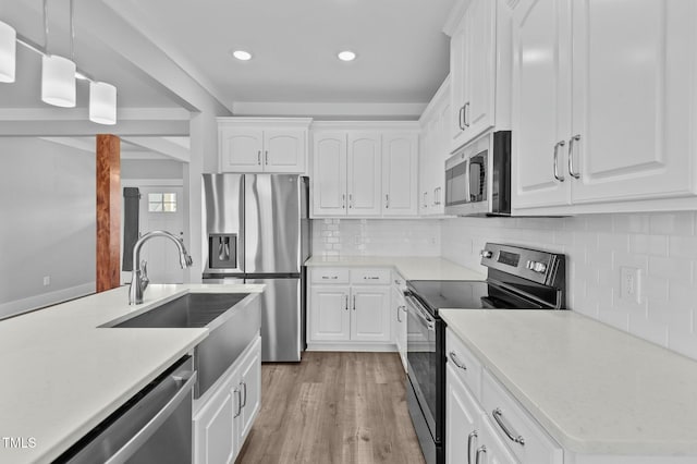 kitchen featuring decorative backsplash, appliances with stainless steel finishes, sink, pendant lighting, and white cabinets