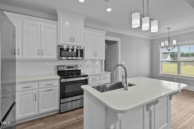 kitchen with backsplash, white cabinetry, stainless steel appliances, and a kitchen island with sink