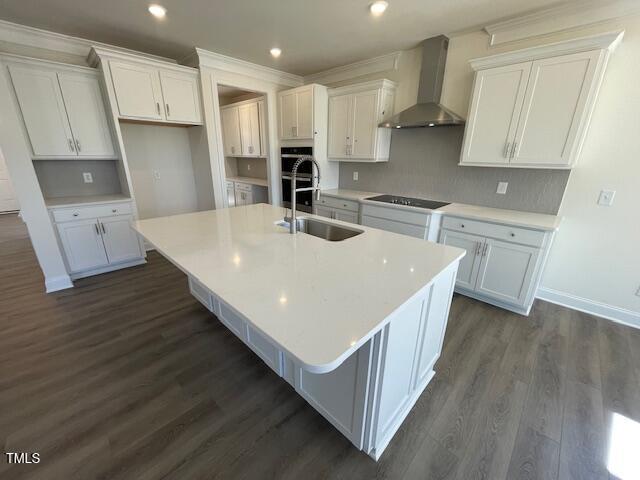 85 N Stagecoach Dr, Wendell, NC 27591 - kitchen with wall chimney range hood, a sink, a center island with sink, white cabinets, and black electric stovetop