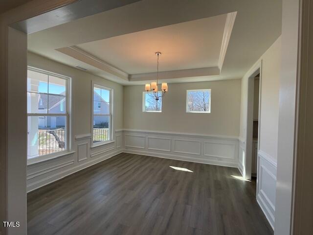 85 N Stagecoach Dr, Wendell, NC 27591 - unfurnished dining area featuring a tray ceiling, a chandelier, dark wood-style floors, a wainscoted wall, and a decorative wall