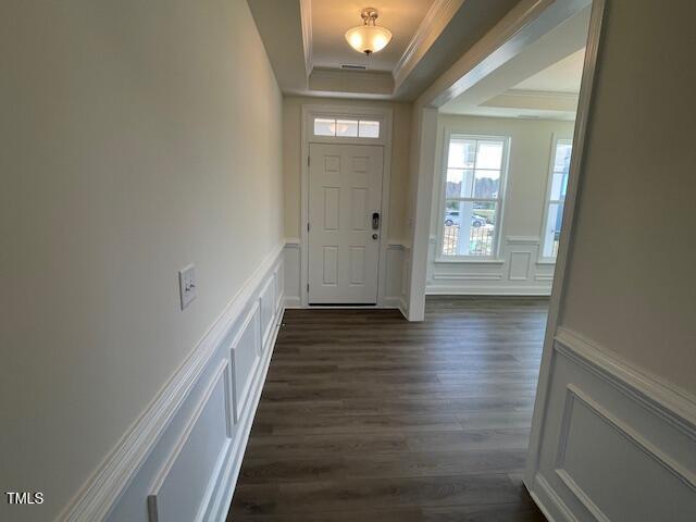85 N Stagecoach Dr, Wendell, NC 27591 - foyer entrance with a decorative wall, ornamental molding, a tray ceiling, dark wood finished floors, and wainscoting