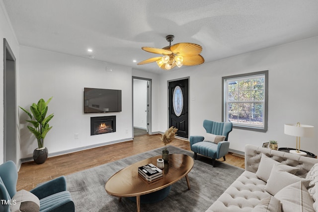 living room featuring hardwood / wood-style floors, ceiling fan, and a textured ceiling