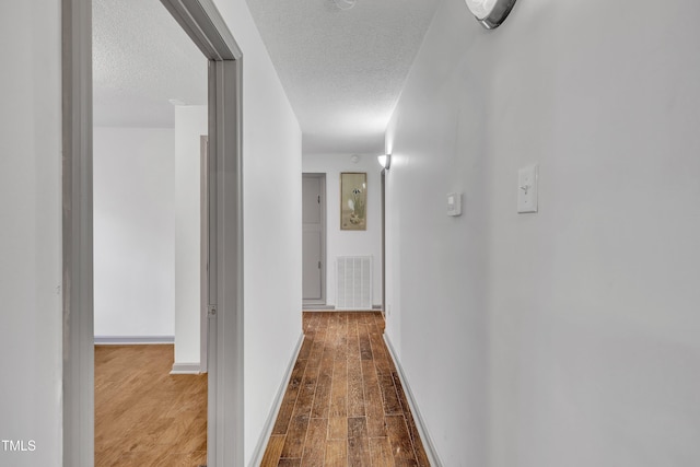 corridor featuring hardwood / wood-style floors and a textured ceiling