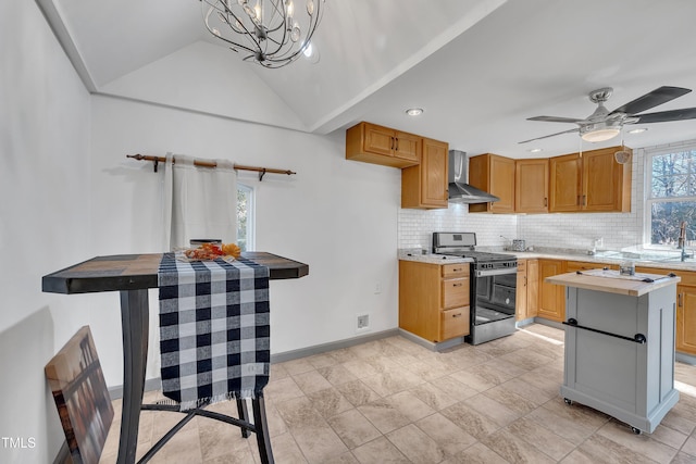 kitchen with tasteful backsplash, stainless steel range, ceiling fan with notable chandelier, vaulted ceiling, and wall chimney range hood