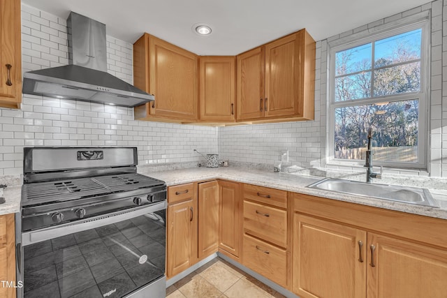 kitchen featuring sink, wall chimney exhaust hood, light stone counters, stainless steel range oven, and light tile patterned flooring