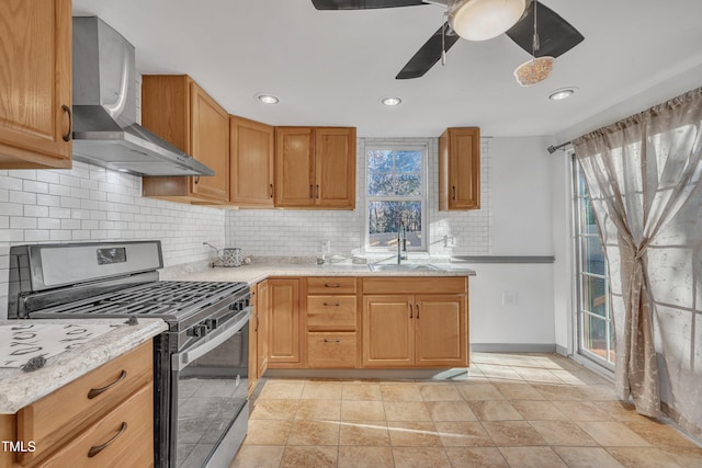 kitchen featuring light stone countertops, a healthy amount of sunlight, wall chimney range hood, and stainless steel range with gas stovetop