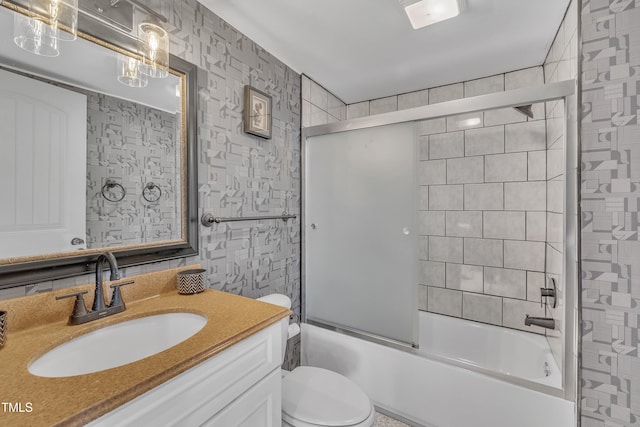 full bathroom featuring vanity, bath / shower combo with glass door, and toilet