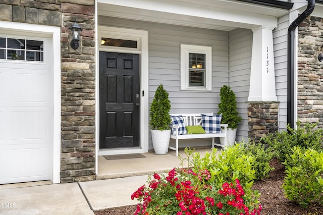 doorway to property with covered porch and a garage