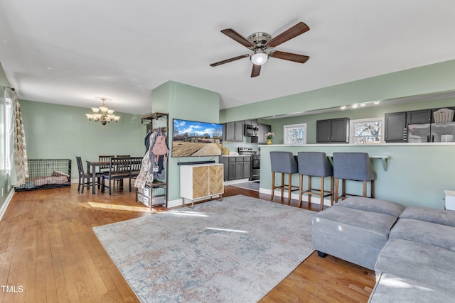 living room with light hardwood / wood-style flooring and ceiling fan with notable chandelier