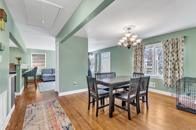 dining room with light wood-type flooring and an inviting chandelier