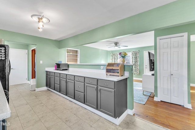 kitchen with gray cabinetry, ceiling fan, and black fridge