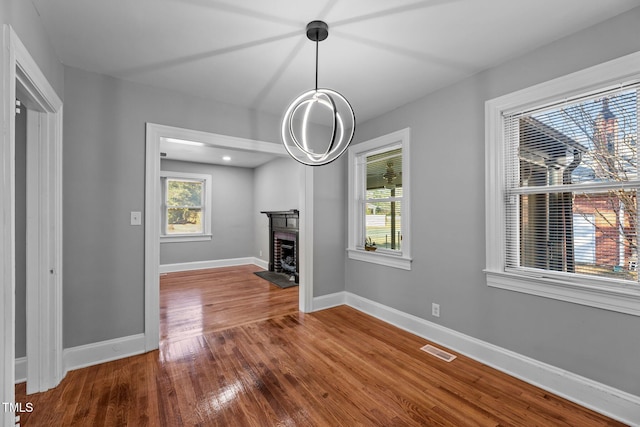 unfurnished living room with plenty of natural light, hardwood / wood-style floors, and a brick fireplace