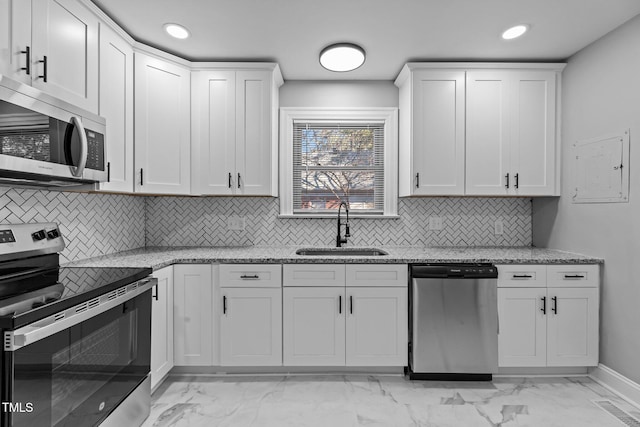 kitchen with stainless steel appliances, sink, white cabinets, and light stone counters