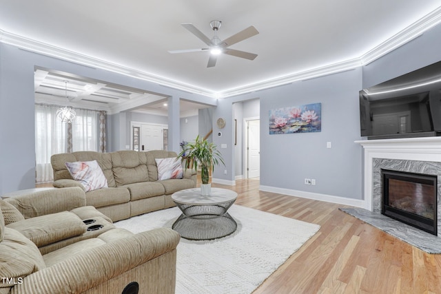 living area featuring coffered ceiling, a high end fireplace, baseboards, light wood-style floors, and ornamental molding