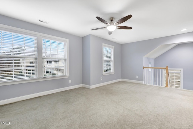 carpeted empty room featuring ceiling fan, visible vents, and baseboards