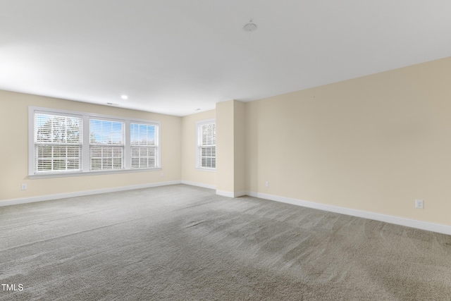 empty room with recessed lighting, light carpet, plenty of natural light, and baseboards