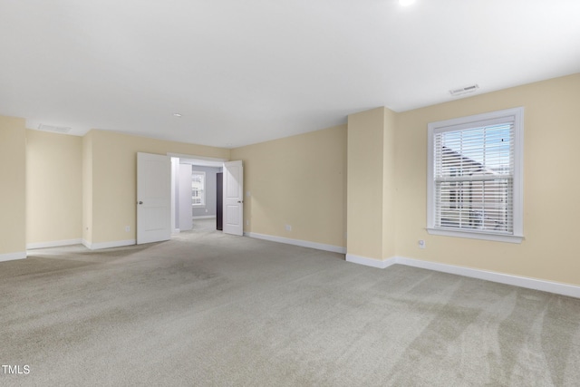 empty room with carpet, visible vents, and baseboards