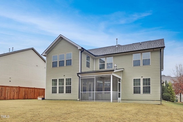 back of property featuring a shingled roof, a lawn, fence, and a sunroom