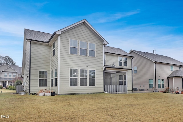 rear view of property with a yard, central AC unit, a shingled roof, and a sunroom