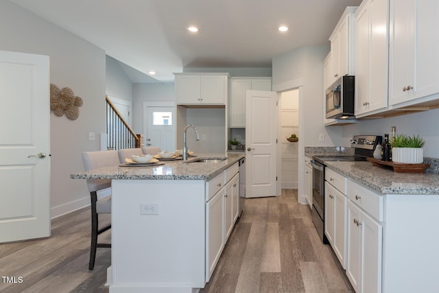 kitchen with white cabinetry, sink, a center island with sink, and appliances with stainless steel finishes