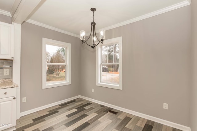 unfurnished dining area with light hardwood / wood-style floors, ornamental molding, a healthy amount of sunlight, and an inviting chandelier