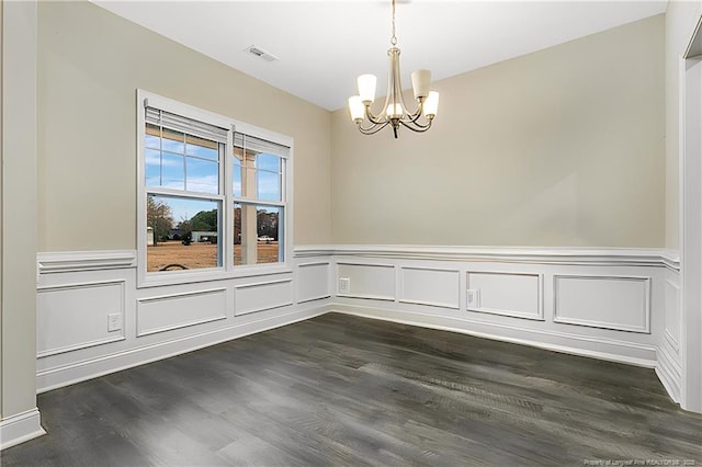 spare room with a notable chandelier and dark hardwood / wood-style flooring